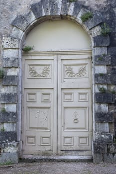 A double door in wood framed by a stone bulding