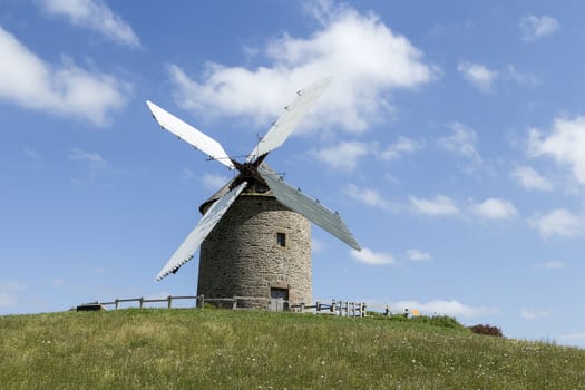 A wind mill in France on a hill with blue sky