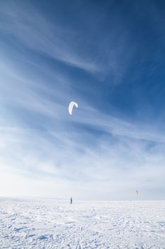 Kite surfer being pulled by his kite across the snow