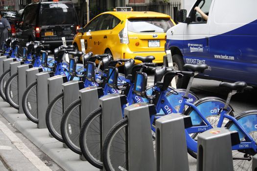 NEW YORK CITY, NY - MAY 27, 2015 - Midtown Manhattan street with a Citibike station filled with bikes for rent. The fleet of bikes is used in a new bike sharing system throughout the city.