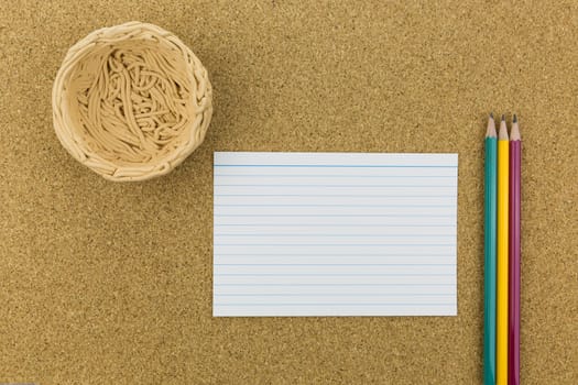 ceramic nest on cork board with paper and pencils