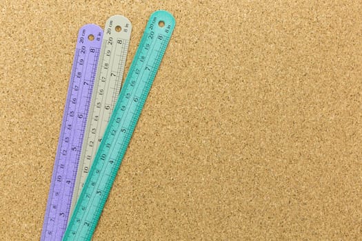 three color of rulers place on cork board with space