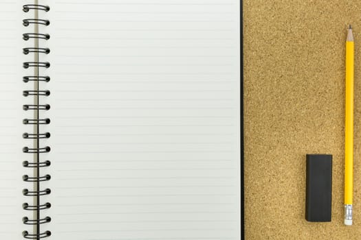 white notebook with line on cork board with pencil and eraser