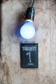 Success concept, light and inscription on a wooden table.