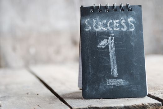 Success concept, chalk inscription and wooden table.