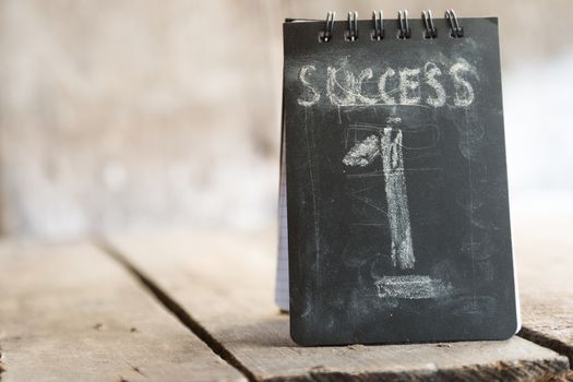 Success, first concept, chalk inscription and wooden table.