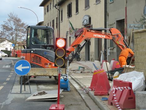 SIENA, ITALY - CIRCA DECEMBER 2014: road construction site with caterpillar, traffic signs and traffic light
