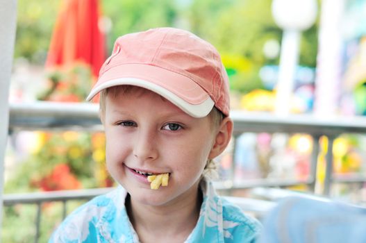 funny cute boy in cafe eating french fries