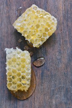 Honeycomb and honey drops over old wooden table