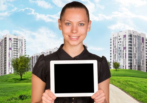 Businesswoman holding tablet and cityscape under blue sky 