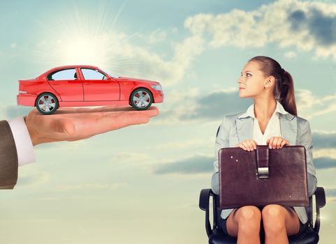 Businesswoman sitting in chair and looking at red car in mans hand