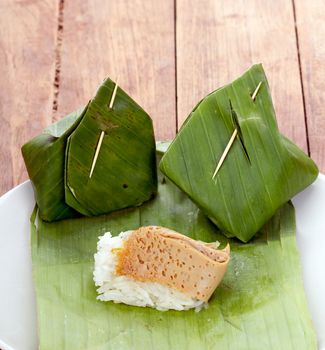 Thai Dessert - Sticky Rice with Egg Custard warpped by banana leaf on white dish