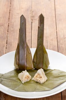 Thai Dessert - Grated Coconut Pudding wrapped by banana leaf - cooked by steam called 'Khanom Sod-Sai' on white dish