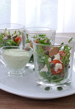 Salad of arugula with cherry tomatoes, capers and feta in a glass