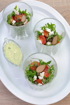 Salad of arugula with cherry tomatoes, capers and feta in a glass