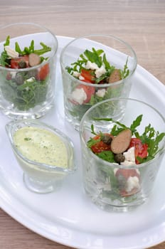 Salad of arugula with cherry tomatoes, capers and feta in a glass