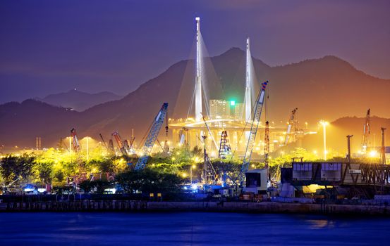 Container Cargo freight ship with working crane bridge in shipyard at dusk for Logistic Import Export background