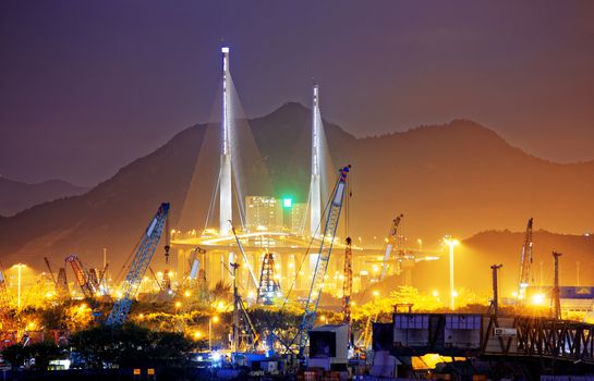 Container Cargo freight ship with working crane bridge in shipyard at dusk for Logistic Import Export background