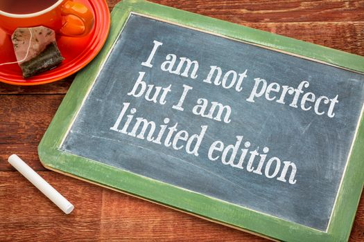I am not perfect but I am limited edition - individuality concept  on a slate blackboard with chalk and cup of tea