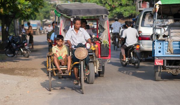 Sittwe, Rakhine State, Myanmar - October 15, 2014: Bicycle taxi navigating the traffic in Sittwe, the capital of the Rakhine State in Myanmar.