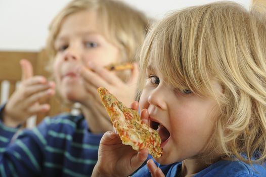 Two young boys enjoy a slice of pizza