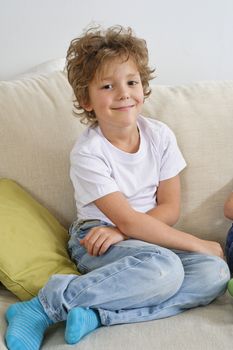Young boy sitting on sofa looking at camera