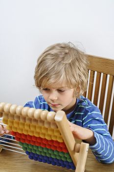 A young boy learns to count using an abacus