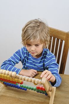 A young boy learns to count using an abacus