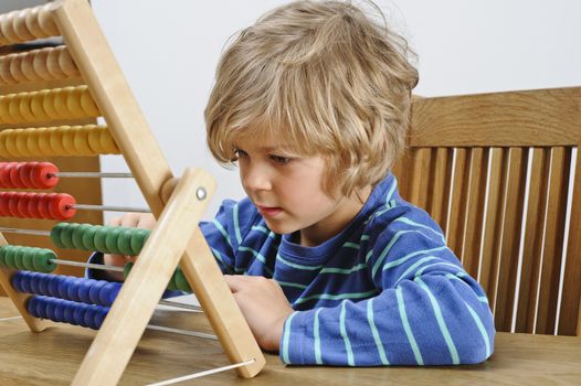 A young boy learns to count using an abacus