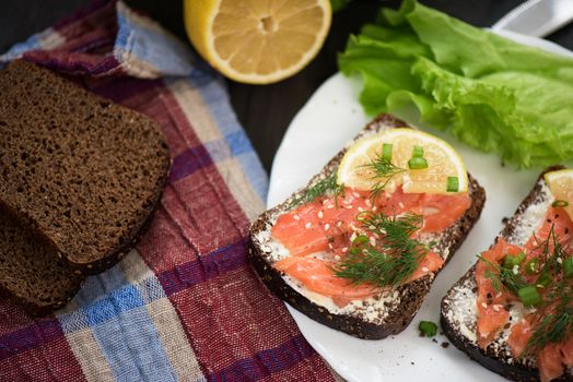 Homemade sandwich with salmon and rye bread , butter lemon, and lettuce for breakfast