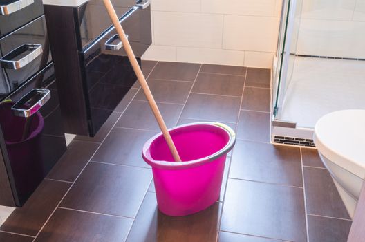 Spring cleaning bucket with mop on a tiled floor.