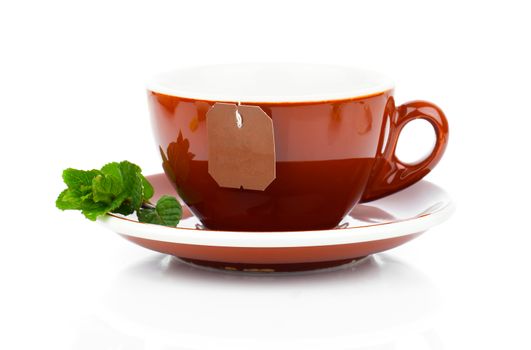 Cup of tea with tea bag and mint plant (blank label) on white background
