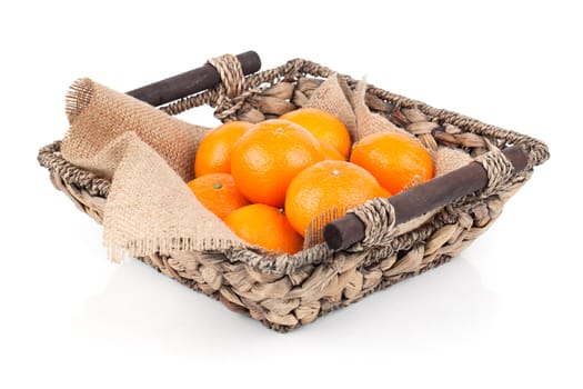 A wicker basket full of fresh orange fruits, isolated on a white background.