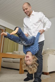 A young boy does somersaults with his father's help.