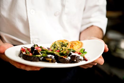 Cropped image of chef showing salad of aubergine
