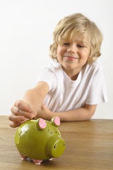 young boy puts a coin into his piggy bank