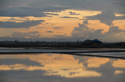 The reflection of clouded sky on salt pan field.