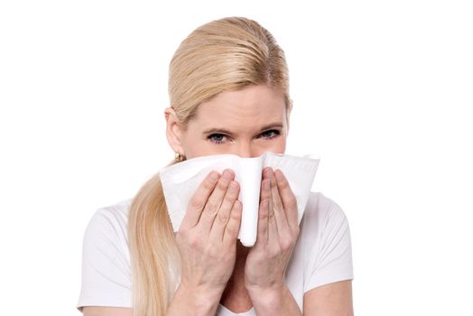 Sick woman blowing her nose into a tissue