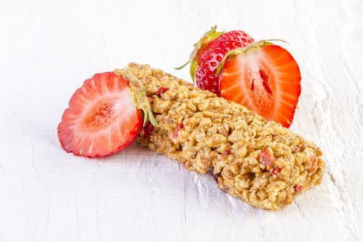 muesli bars with fresh strawberry on white wooden background