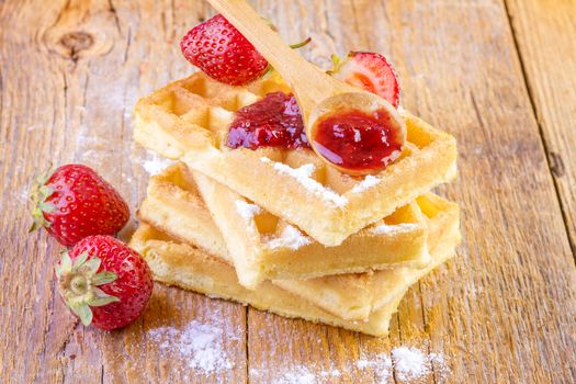 homemade waffles with strawberries maple syrup on wooden background