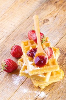 homemade waffles with strawberries maple syrup on wooden background