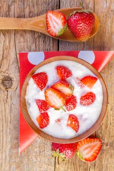 strawberry and yogurt in a wooden bowl on wooden background