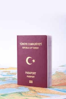 Close up detailed view of a Turkish passport standing on a world map, isolated on white background.