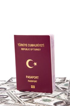 Close up front view of a Turkish passport on one hundred dollar banknotes, isolated on white background.