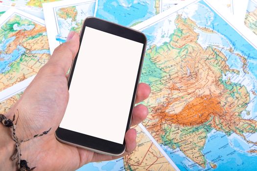 Close up detailed view of a smartphone with blank screen holding on hand on a world map.