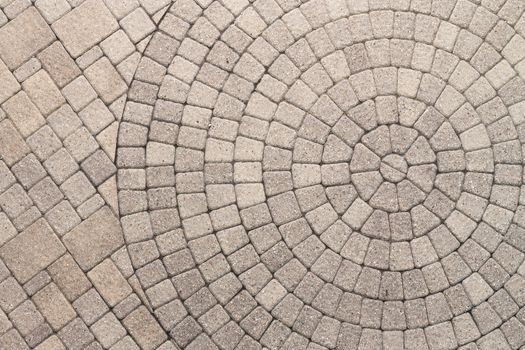 Paver bricks arranged in a circular pattern of concentric geometric circles. Architectural background of an ornamental pattern in outdoor patio paving.