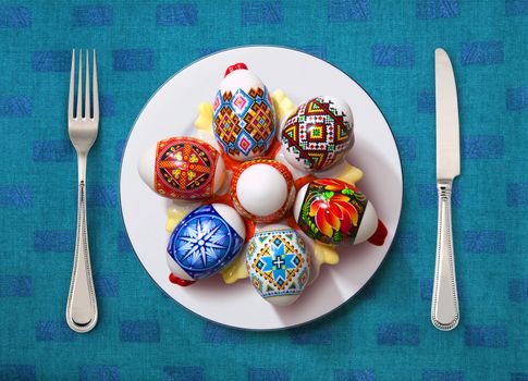 easter egg on white plate, knife and fork on table