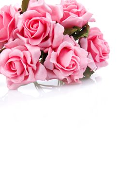 artificial pink roses on a white background with space for greetings