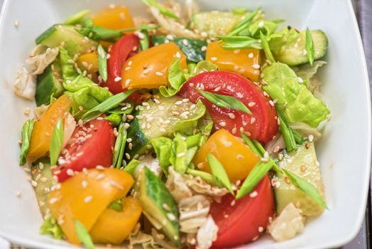 Bulgarian salad from pepper, cucumbers, tomato, green onion with sesame and oil