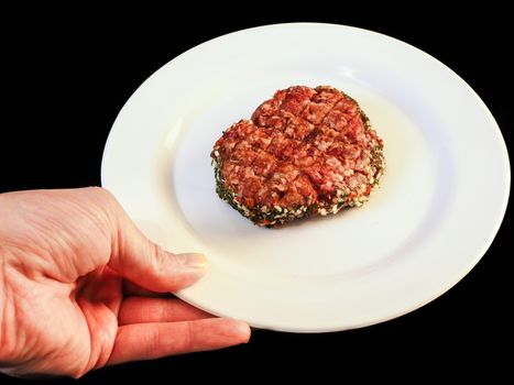 Serving raw burger on white plate isolated on black